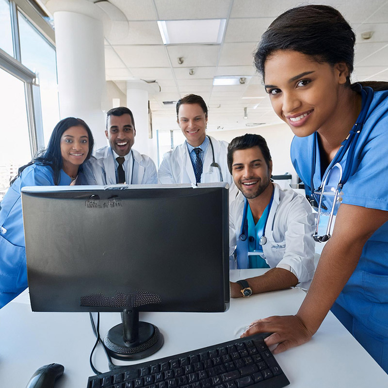 Home Medical Office workers standing around a computer using EDI for Medical Billing